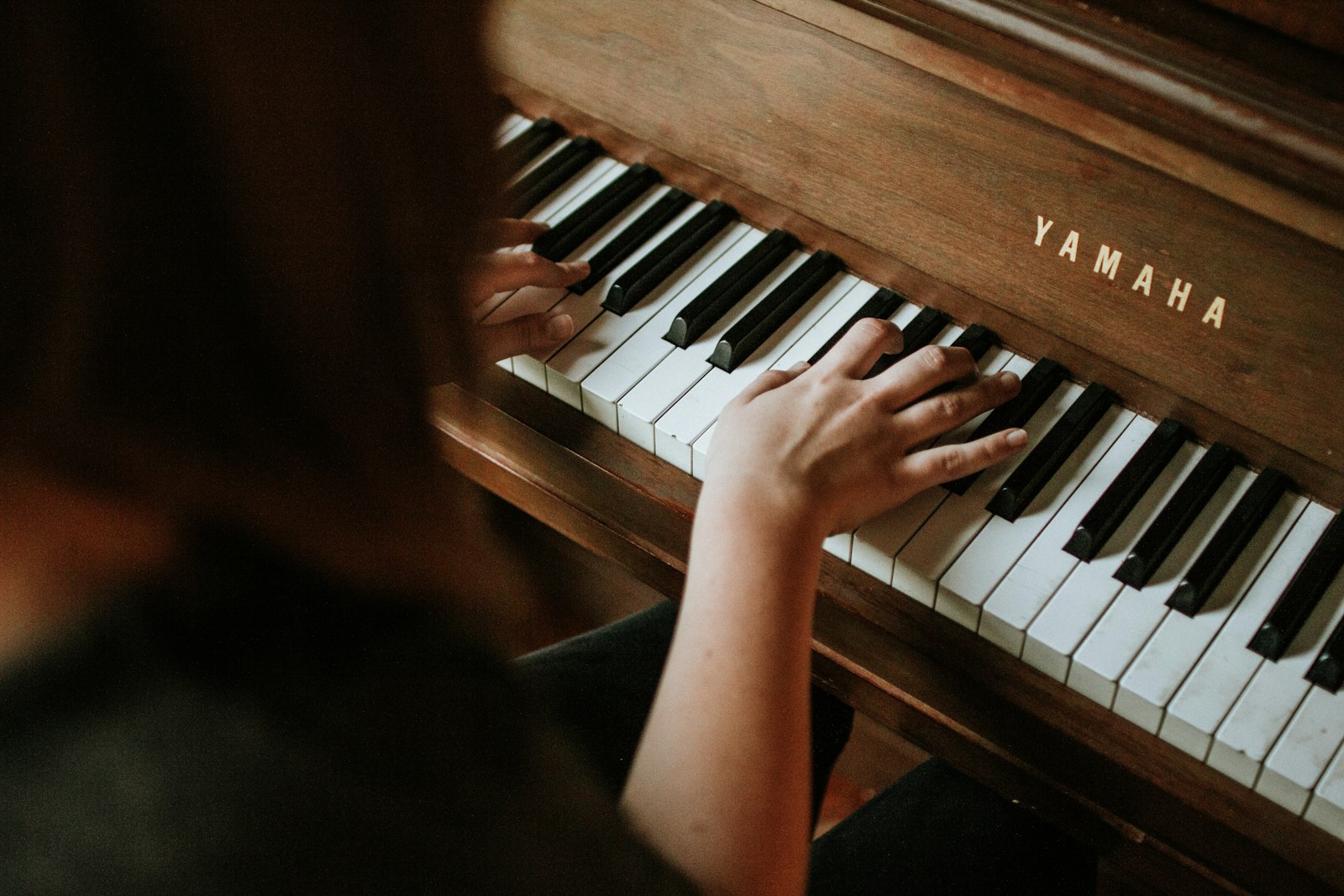 Hands at a piano, warm low light