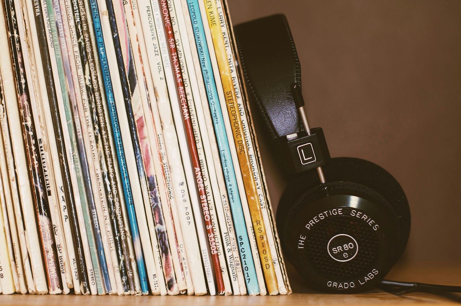 A row of vinyl records with headphones resting on the sleeves