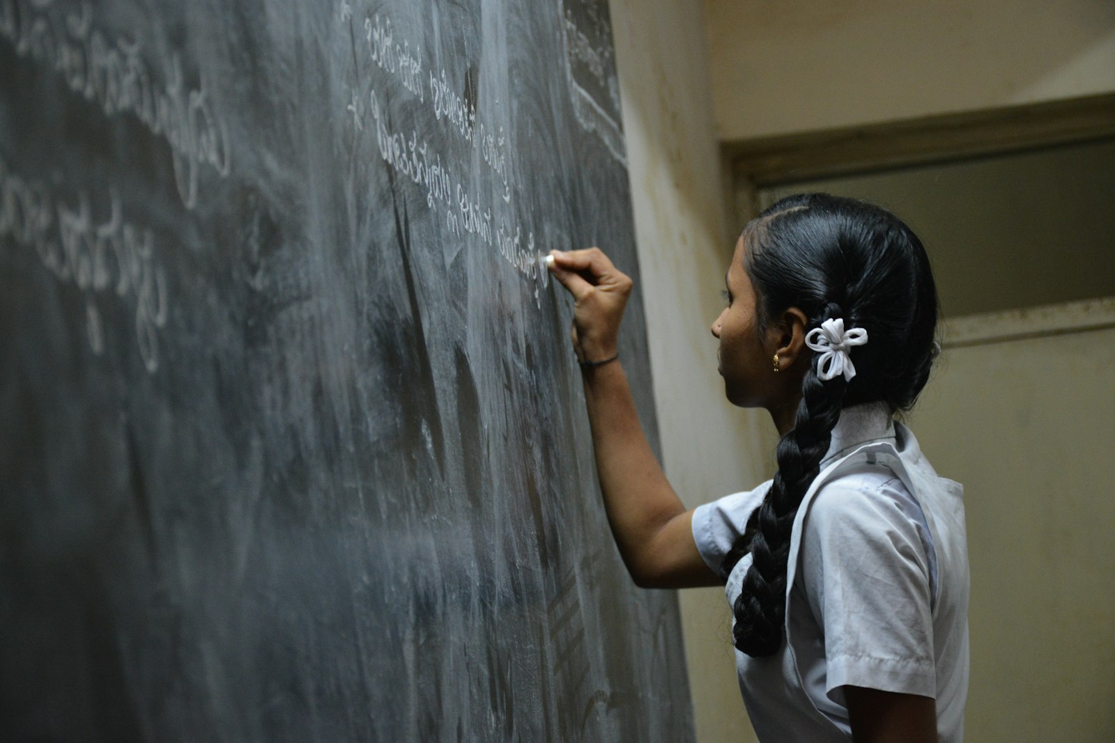 A girl writing on a chalkboard in a quiet classroom